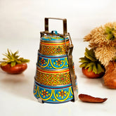 A hand-painted 4 tier steel tiffin box with gold and blue geometric patterns, displayed against a white background with decorative elements.