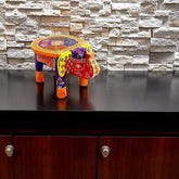 Colorful elephant-shaped table on a dark surface with a stone wall background