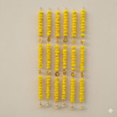 Yellow beaded hanging decorations on a beige background