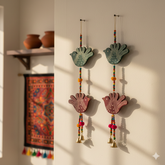 Decorative wall hangings with hand-shaped designs and colorful beads on a neutral wall.