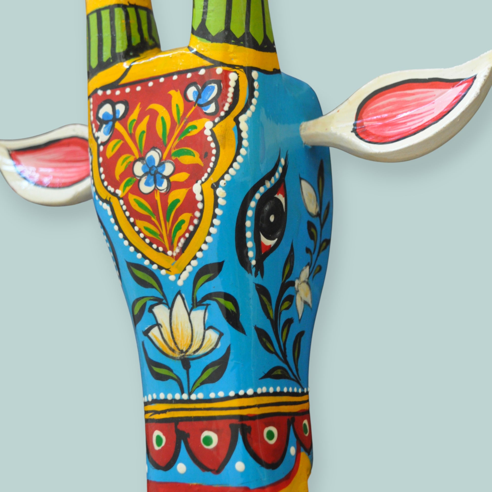 Decorative cow head sculpture with colorful patterns on a light blue background