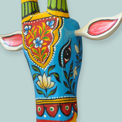 Decorative cow head sculpture with colorful patterns on a light blue background